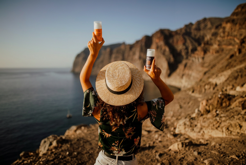 Woman in a sunhat holding Nurme natural beauty oils beside the sea