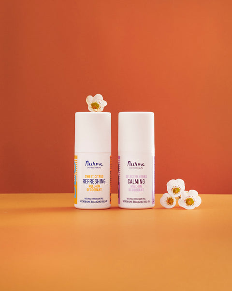Nurme natural Sweet Citrus and Selected Herbs roll-on deodorants beside white flowers
