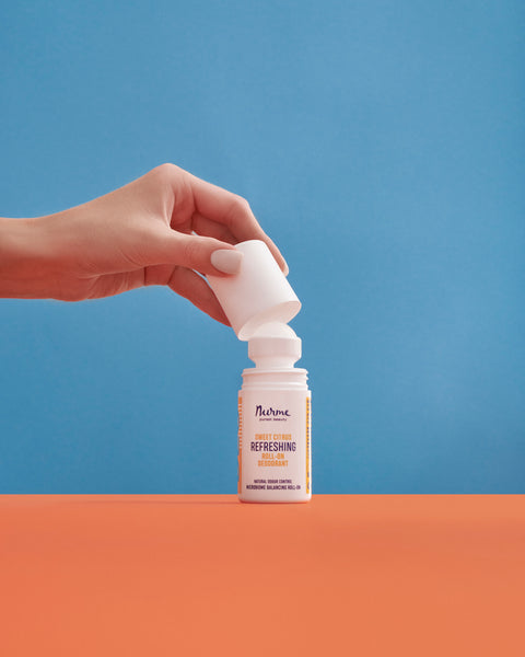 Hand lifting the cap from Nurme natural Sweet Citrus roll-on deodorant